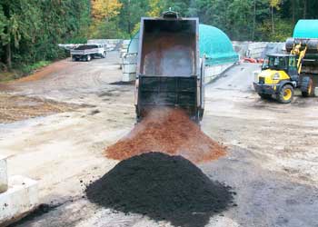 truck dumping topsoil and bark mulch in piles