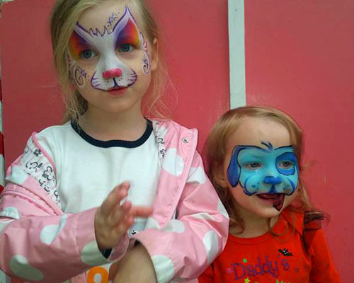 two girls with face painted like a cat and other like a puppy in blue