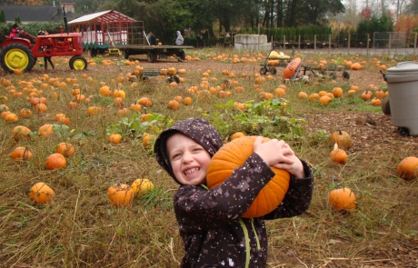 Child hugging pumpkin in pumpkin patch