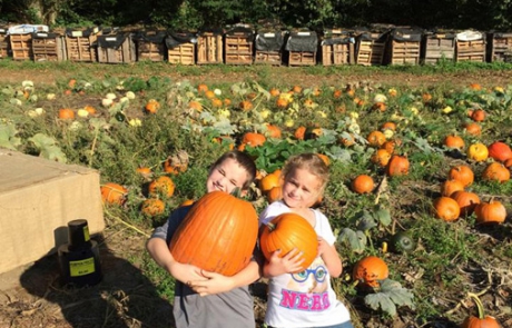 two kids with pumpkins in the pumpkin patch